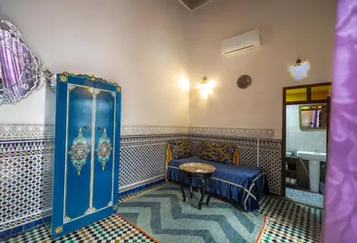 a room with a bed and a sink and a table at Riad Arabella in Fès