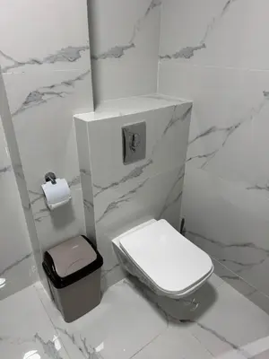 a white bathroom with a toilet and a trash can at HOTEL BORJ EL ARAB in Khouribga