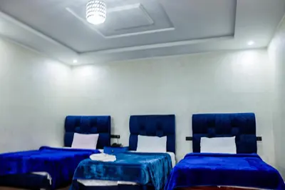 two beds in a room with blue chairs at HOTEL BORJ EL ARAB in Khouribga