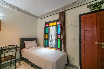 a bedroom with a bed and a stained glass window at 105 Kasbah de Boujloud Fes Morocco. in Fès