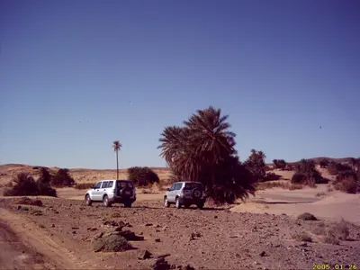 two vehicles parked on a dirt road in the desert at chez zakaria à Merzouga in Merzouga