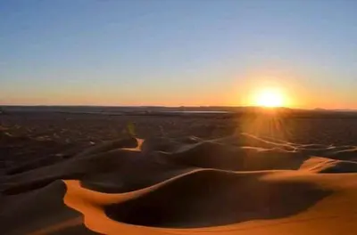 a sunset over a field of sand dunes at chez zakaria à Merzouga in Merzouga