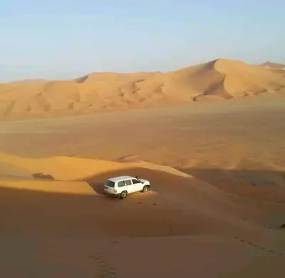 a white car parked in the middle of a desert at chez zakaria à Merzouga in Merzouga