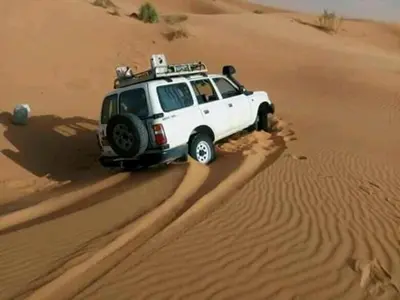 a white suv driving in the desert at chez zakaria à Merzouga in Merzouga