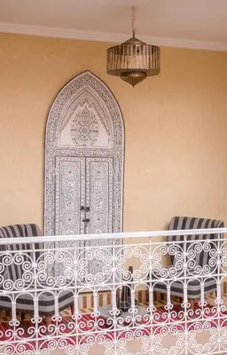a room with a bed with a door with chairs at Riad Chebbi in Merzouga
