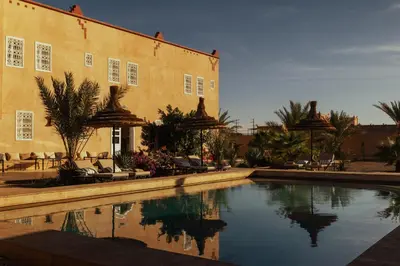 a building with a swimming pool in front of a building at Riad Chebbi in Merzouga