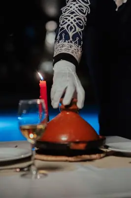 a person is lighting a candle next to a glass at Riad Chebbi in Merzouga