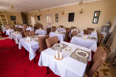 a dining room with white tables and chairs at Riad Chebbi in Merzouga