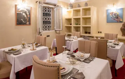 a restaurant with tables and chairs with white tablecloths at Riad Chebbi in Merzouga