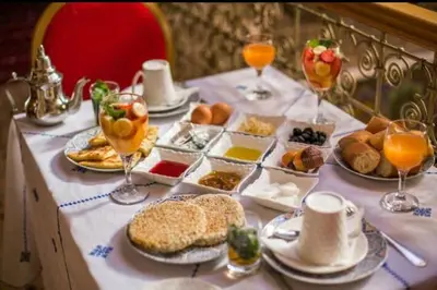 a table topped with plates of food and glasses of orange juice at PALAIS LARAICHI Riad la porte bleue suites in Fès