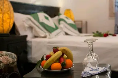 a bowl of fruit on a table next to a bed at PALAIS LARAICHI Riad la porte bleue suites in Fès