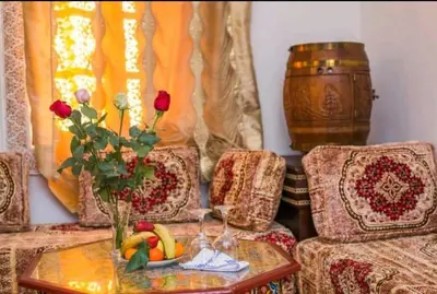 a living room with a table with a vase of roses at PALAIS LARAICHI Riad la porte bleue suites in Fès
