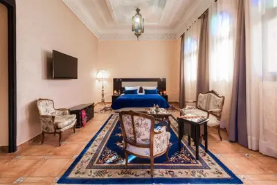 a bedroom with a bed and a table and chairs at La Citadelle Marrakech in Marrakech