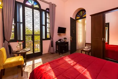 a bedroom with a red bed and windows at La Citadelle Marrakech in Marrakech