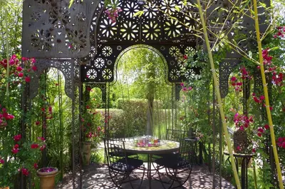 an arbor with a table in a garden with flowers at La Citadelle Marrakech in Marrakech