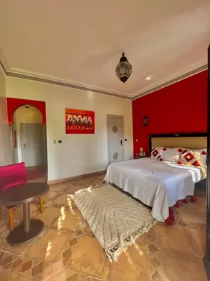 a bedroom with two beds and a red wall at Le Rubis Oriental Marrakech in Azib Oulad Lâdem