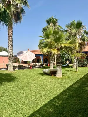 a park with palm trees and an umbrella at Le Rubis Oriental Marrakech in Azib Oulad Lâdem