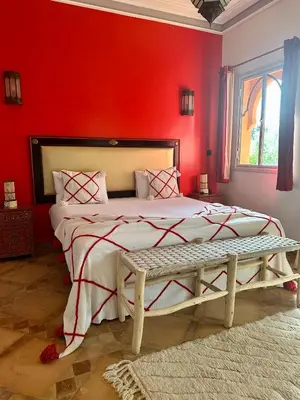 a bedroom with a large bed with a red wall at Le Rubis Oriental Marrakech in Azib Oulad Lâdem