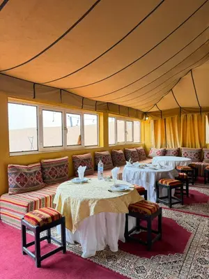 a tent room with tables and couches and windows at Le Pacha Luxury Desert Camp - Mhamid Sahara Activities in Mhamid