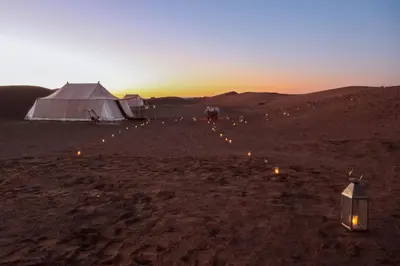 a group of tents in the desert at sunset at Le Pacha Luxury Desert Camp - Mhamid Sahara Activities in Mhamid