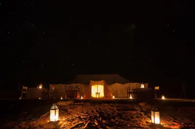 a tent with lights in the middle of the night at Le Pacha Luxury Desert Camp - Mhamid Sahara Activities in Mhamid