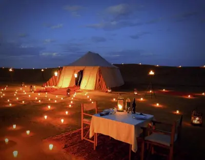 a tent with a table and chairs and lights at Le Pacha Luxury Desert Camp - Mhamid Sahara Activities in Mhamid