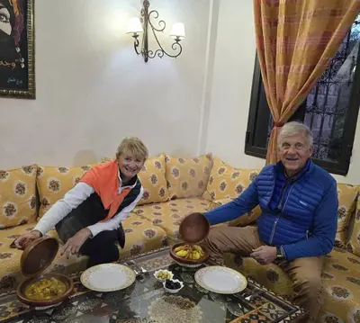 an older couple sitting on a couch with plates of food at Les Jardins Yasmina Bin el-Ouidane in Bine el Ouidane