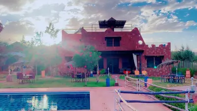 a red house with a pool in front of it at Les Jardins Yasmina Bin el-Ouidane in Bine el Ouidane