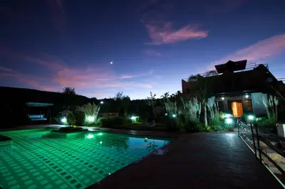 a large swimming pool at night with lights on at Les Jardins Yasmina Bin el-Ouidane in Bine el Ouidane