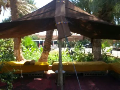 a large wooden umbrella with a couch under it at Auberge jnane dar diafa se trouve au centre de tamegrouteface de la bibiotheque in Tamegroute