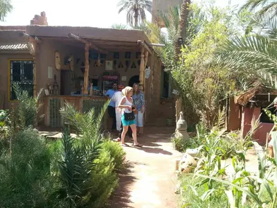 a group of people standing outside of a house at Auberge jnane dar diafa se trouve au centre de tamegrouteface de la bibiotheque in Tamegroute