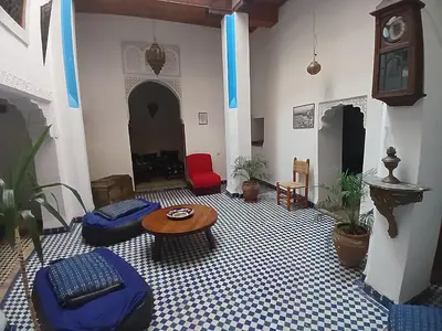 a living room with a table and chairs and a clock at Riad Dar Mystère in Fès