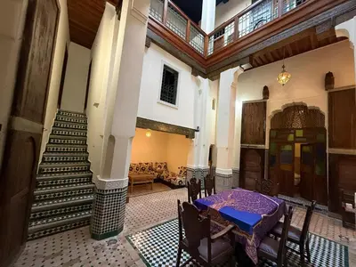 a dining room with a table and stairs in a building at Riad Ranya in Fès