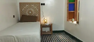 a bedroom with a bed and a table with a lamp at Riad Ranya in Fès