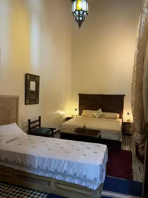 a bedroom with two beds and a chandelier at Riad Ranya in Fès