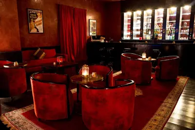 a restaurant with red chairs and a table and a bar at Boutique Hôtel palais Masandoia in Erfoud