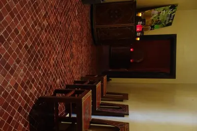 a row of wooden stools against a red tiled wall at Boutique Hôtel palais Masandoia in Erfoud