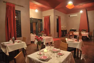 a dining room with white tables and chairs and red curtains at Boutique Hôtel palais Masandoia in Erfoud