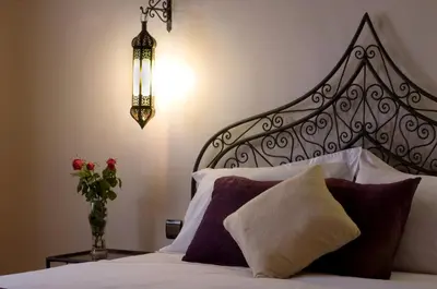a bedroom with a bed with a headboard and a vase of flowers at Riad Bouchedor in Ouarzazate