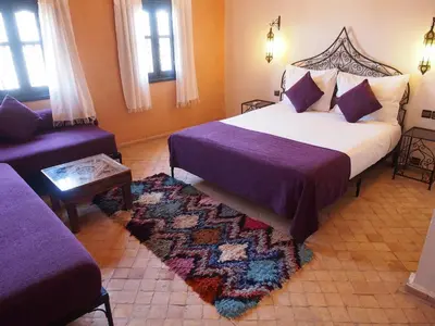 a bedroom with a large bed and a couch at Riad Bouchedor in Ouarzazate