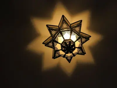 a light fixture on a wall with a shadow at Riad Bouchedor in Ouarzazate