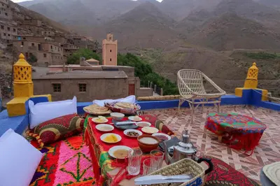 a table with food on a balcony with mountains at Dar Bejmate - Chez Hassan in Tacheddirt