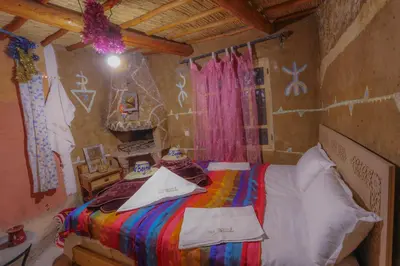 a bedroom with a bed with a colorful blanket at Dar Bejmate - Chez Hassan in Tacheddirt