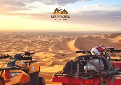 two atvs in the desert with the words las motorcycles desert camp at Les Roches Desert Camp in Merzouga