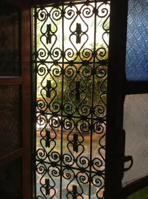 an open door with a gate with a window at Riad Timadrouine, hôtel et restaurant in Tinerhir