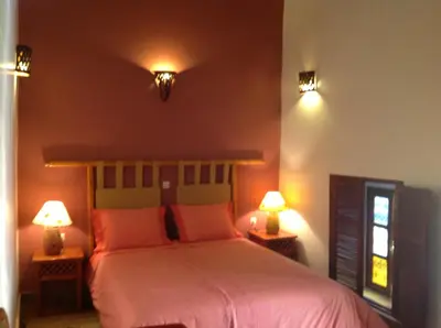 a bedroom with a bed with pink sheets and two lamps at Riad Timadrouine, hôtel et restaurant in Tinerhir