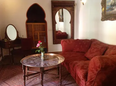 a living room with a red couch and a table at Riad Timadrouine, hôtel et restaurant in Tinerhir