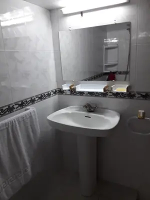 a white bathroom with a sink and a mirror at Appartement Moderne 3 Chambres in Fès