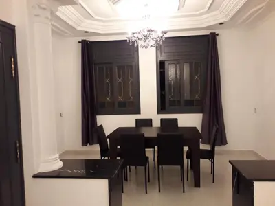 a dining room with a black table and black chairs at Appartement Moderne 3 Chambres in Fès
