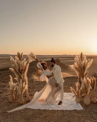 a bride and groom posing for a picture in the desert at Maison Boutchrafine in Erfoud